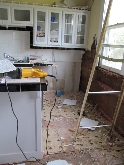 removing linoleum flooring to reveal old hardwood floors and the filth from removing the acoustical ceiling tiles