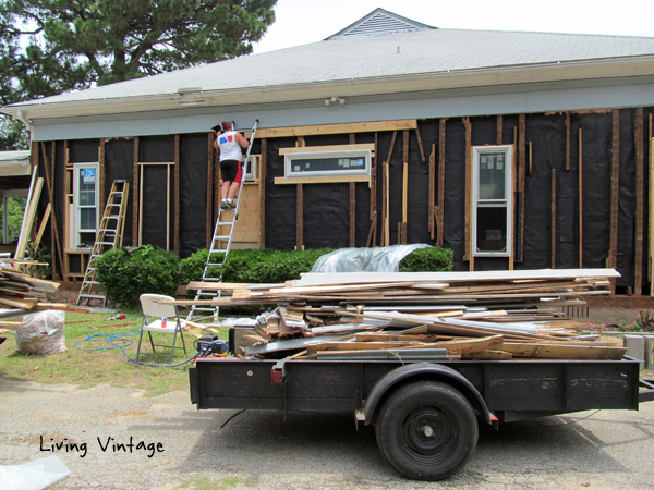 stapling tar paper to the cavities would prevent spray foam from seeping between the cracks of the interior wood walls