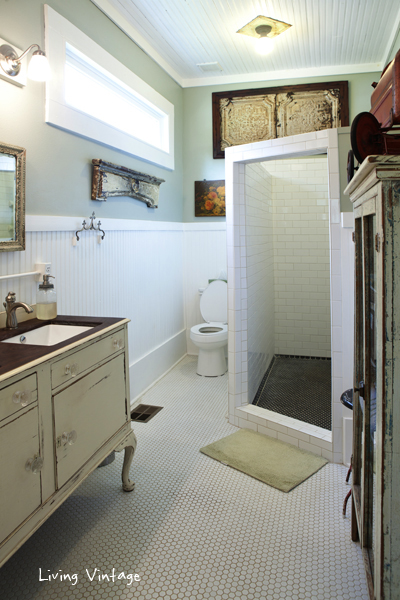 so much vintage including a double sink made with an old buffet, towel storage in an antique cabinet and architectural remnants